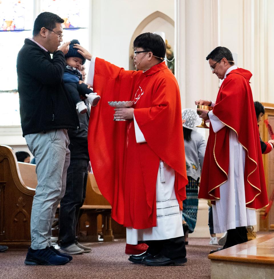 The Rev. Chakrit Micaphitak blesses 6-month-old Mary Pumpau as her father Anthony Pumpau takes the Eucharist during the Palm Sunday Mass at St. Michael's Catholic Church  in Milwaukee.