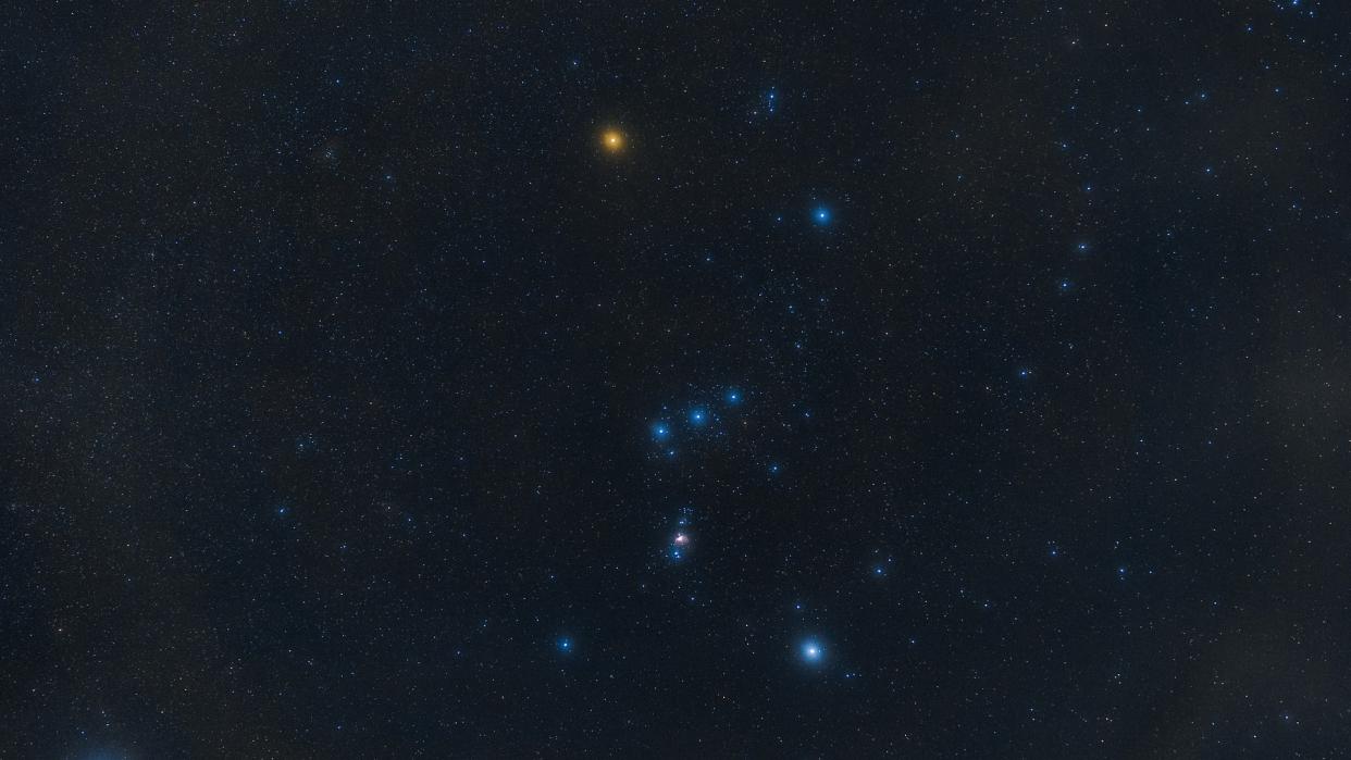  The Orion constellation shines bright in the night sky, with one red star representing the hunter's shoulder. 
