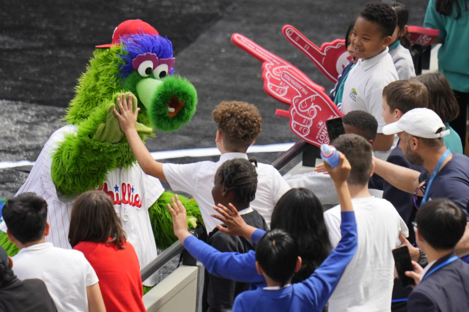 La mascota de los Filis saluda a niños mientras el equipo entrena en el London Stadium, el viernes 7 de junio de 2024. Los Mets de Nueva York jugarán en Londres contra los Filis el 8 y 9 de junio. (AP Foto/Kirsty Wigglesworth)