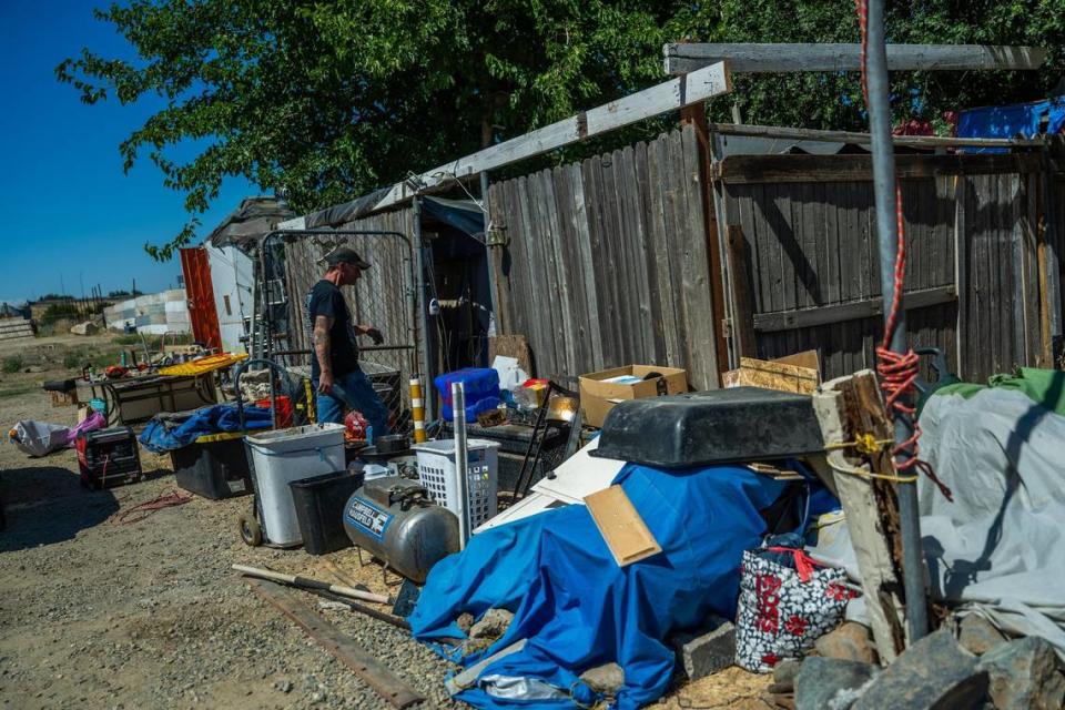 Nikki Buckles, who fell into homelessness after a house fire, lives in a tented area inside a wooden structure he built near Del Paso Park on Tuesday. He said his dog Opium has motivated him to stay safe and healthy, otherwise he would have difficulty surviving the heat.