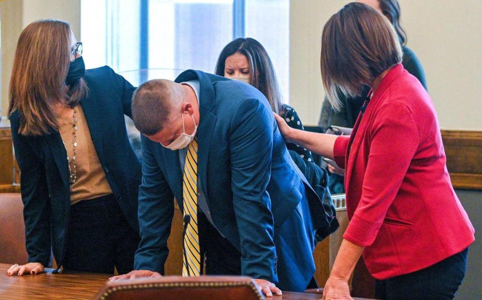 Eric DeValkenaere, center, is comforted by attorneys Dawn Parsons, left, and Molly Hastings, after Jackson County Circuit Court Judge J. Dale Youngs announced on Friday, Nov. 19, 2021, that he found DeValkenaere, a Kansas City police detective, guilty in the fatal December 2019 shooting of Cameron Lamb.