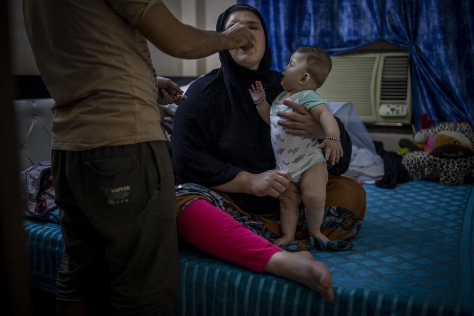 Mohammad Nabi gives medicine to his wife, a former Afghan policewoman Khatera Hashmi, as their seven-month-old daughter looks on inside a rented accommodation in New Delhi, India on Aug. 13, 2021. When the Taliban shot policewoman Khatira Hashmi and gouged out her eyes, she knew Afghanistan was no longer safe. Along with her husband, she fled to India last year. She was shot multiple times on her way home from work last October in the capital of Ghazni province, south of Kabul. As she slumped over, one of the attackers grabbed her by the hair, pulled a knife and gouged out her eyes. (AP Photo/Altaf Qadri)