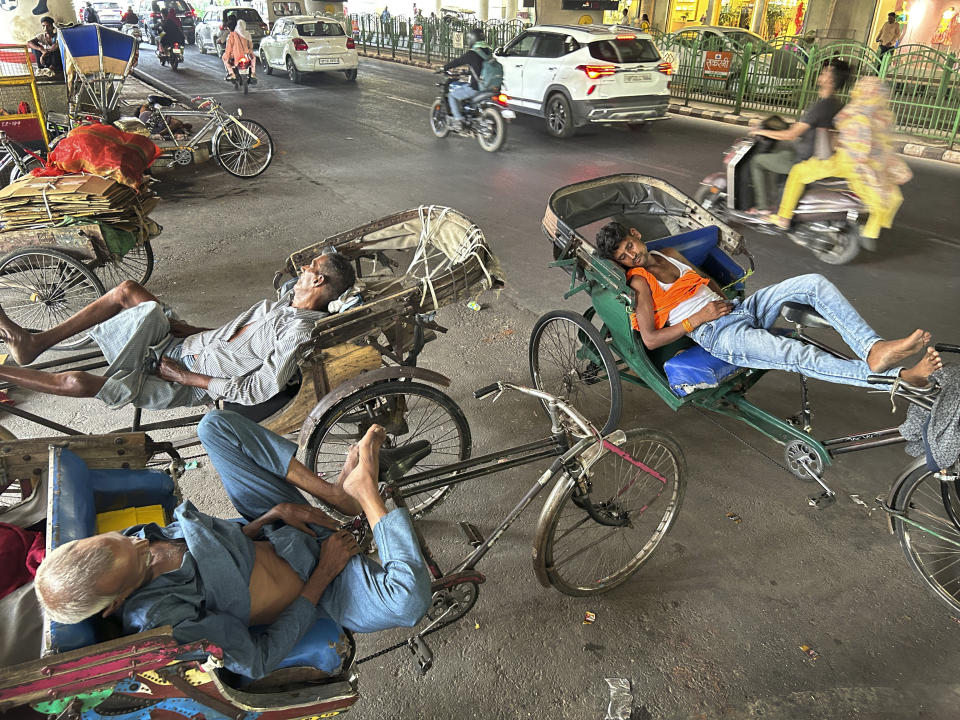 Conductores de rickshaw duermen a la sombra que arroja una línea elevada de metro en una jornada de mucho calor en Lucknow, India, el 27 de mayo de 2024. (AP Foto/Rajesh Kumar Singh)