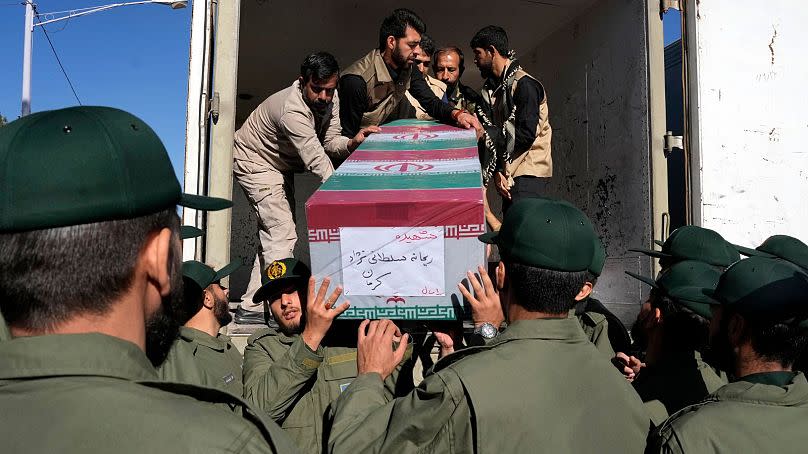 Revolutionary Guard members unload the flag-draped coffin of one of the victims of Wednesday's attack claimed by IS.