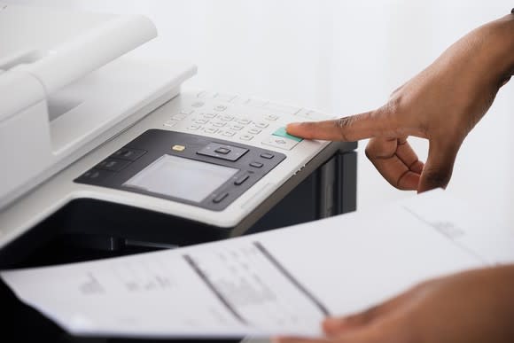 A person puts their finger on a copy machine.