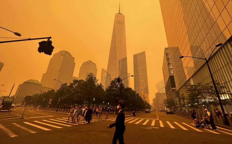 Pedestrians pass the One World Trade CentRE amidst a smokey haze from wildfires in Canada - Julie Jacobson/ap