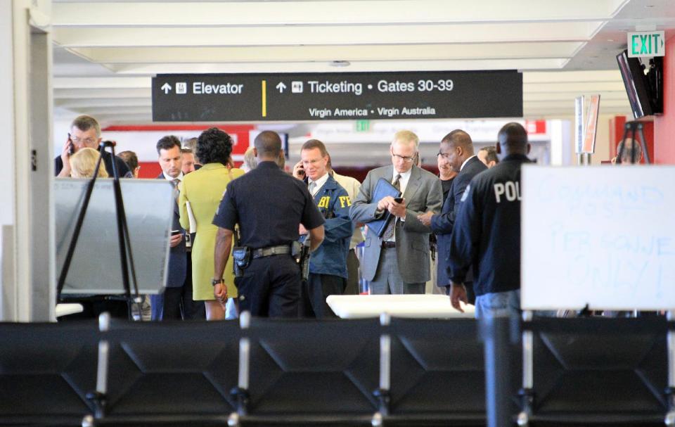 FILE - In this Nov. 1, 2013 file photo, federal and local investigators gather in Terminal 3 at Los Angeles International Airport where a gunman armed with a semi-automatic rifle opened fire, killing a Transportation Security Administration employee and wounding two other people. Two armed police officers, not seen in this photo, assigned to guard the terminal, left for breaks without informing dispatchers as required minutes before the gunfire erupted. (AP Photo/Ringo H.W. Chiu, File)