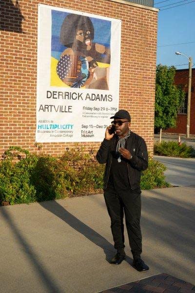 Artist Derrick Adams is seen speaking on the phone next to a poster announcing his artist's talk for Artville in Nashville on Friday. Photo by Adam Schrader/UPI