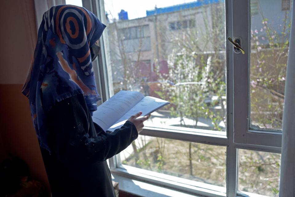 Deena Rahimi, a twelfth-grade student, reads a book at her residence in Kabul on March 21, 2023. Afghanistan's schools reopened in March, but hundreds of thousands of girls remain barred from attending class. / Credit: AHMAD SAHEL ARMAN/AFP via Getty Images