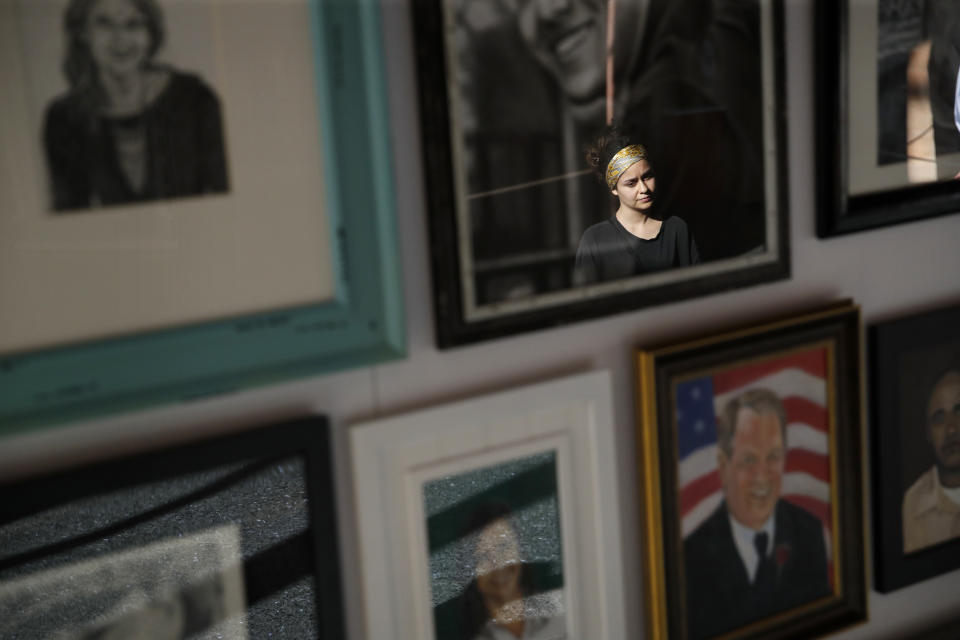 In this Sept. 25, 2018, photo, a woman looks at painted portraits of victims of the Oct. 1, 2017, mass shooting in Las Vegas on display at the Clark County Government Center in Las Vegas. (AP Photo/John Locher)