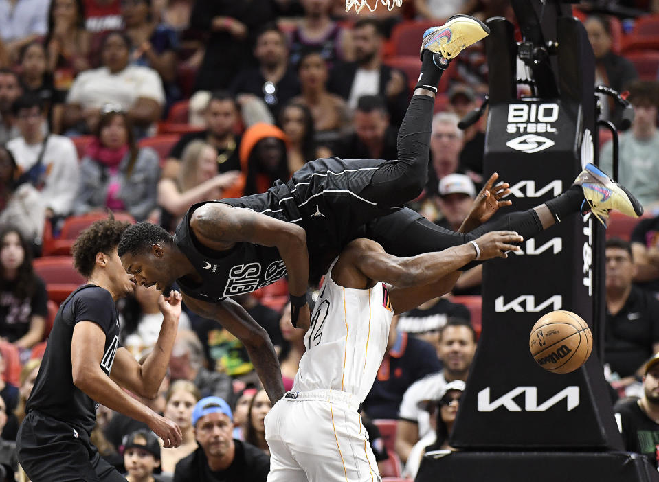 Brooklyn Nets forward Dorian Finney-Smith (28) falls over Miami Heat forward Jimmy Butler (22) during the first half of an NBA basketball game, Saturday, March 25, 2023, in Miami, Fla. (AP Photo/Michael Laughlin)