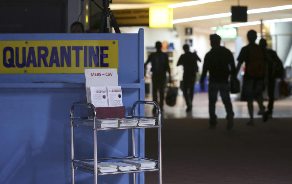 FILE - In this Wednesday, April 16, 2014, file photo, passengers walk past the medical quarantine area showing information sheets for the Middle East respiratory syndrome coronavirus at the arrival section of Manila's International Airport in Paranaque, south of Manila. One expert says recent outbreaks of MERS in Saudi Arabia and the United Arab Emirates that led to more than 20 infections, many among health-care workers, “have put us into uncharted territory.”Saudi Arabia’s King Abdullah sacked the country’s health minister on Monday, April 21, 2014, amid a spike in deaths and infections from the virus known as the Middle East respiratory syndrome, or MERS. The official Saudi Press Agency carried the royal order that said Abdullah al-Rabiah was relieved of his post as Health Minister, and that Labor Minister Adel Faqih will temporarily take over the health minister’s portfolio until a replacement is named. The statement said al-Rabiah is now adviser to the Royal Court. (AP Photo/Aaron Favila, File)