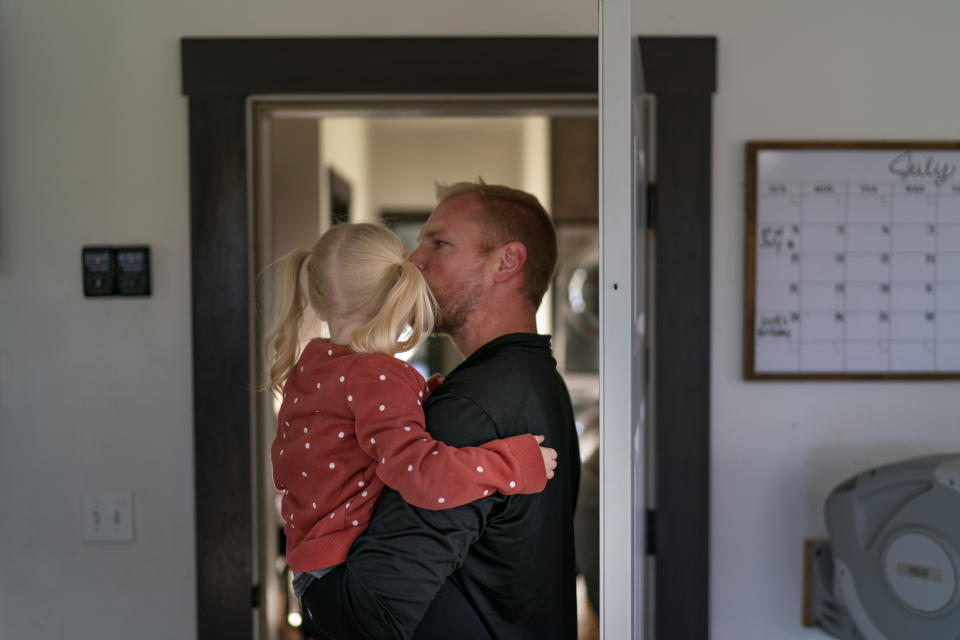 Scott Miller kisses his daughter at their home in Baldwin, Wis., Friday, Sept. 30, 2022. In this picturesque corner of western Wisconsin, a growing right-wing conservative movement has rocketed to prominence and are a cornerstone of the conservative electoral base. They, like Miller, a sales analyst, see America as a country where the most basic beliefs, in faith, family, liberty, are threatened. (AP Photo/David Goldman)