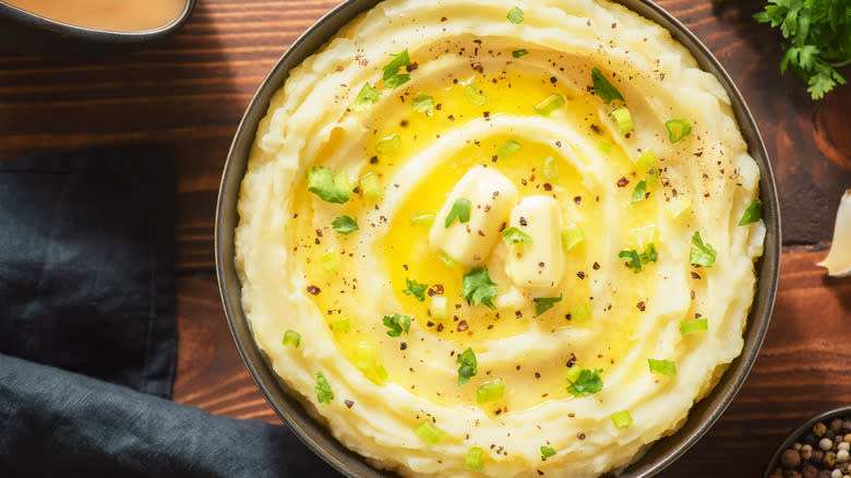 A bowl of mashed potatoes with melted butter and herbs