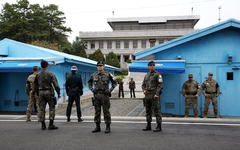U.S. and South Korean soldiers, foreground, and North Korean soldiers, background, stand guard next to the meeting rooms that straddle the border between the two Koreas - Credit:  SeongJoon Cho/Bloomberg