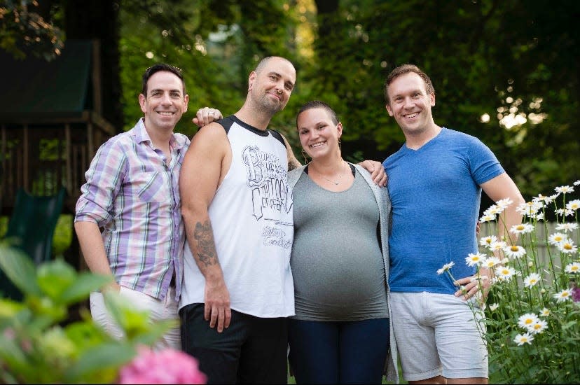 Maureen Farris (center) shown with her husband Jeremiah Currier (second from left) was the surrogate for three identical girls for new dads Kevin O'Neill (left) and Eric Portenga (right).