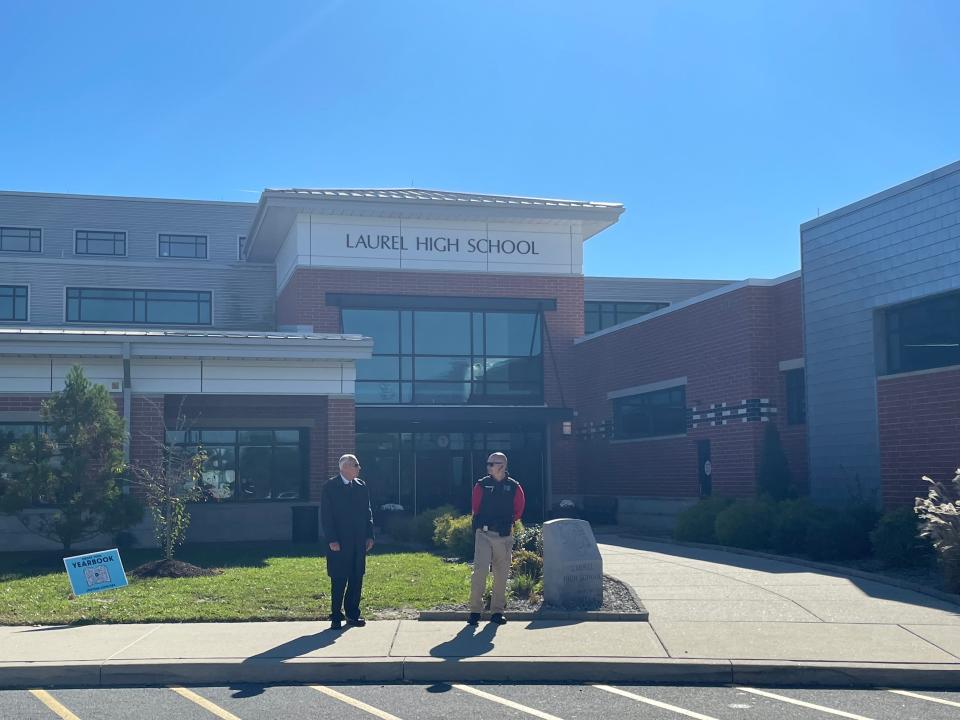 A funeral director and a school constable stand at the entrance to Laurel High School as people enter for Kylee Robinson's funeral.