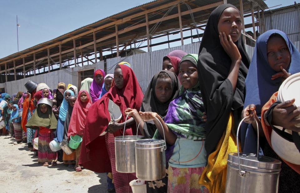 In this photo taken Saturday, Feb. 25, 2017, displaced Somali girls who fled the drought in southern Somalia stand in a queue to receive food handouts at a feeding center in a camp in Mogadishu, Somalia. Thousands of desperate people are streaming into Somalia's capital seeking food as a result a prolonged drought, overwhelming local and international aid agencies, while the Somali government warns of a looming famine, compounded by the country's ongoing conflict against Islamic extremists. (AP Photo/Farah Abdi Warsameh)