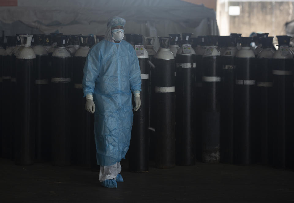 A front-line worker passes oxygen ciylinders at the Steve Biko Academic Hospital's outside parking area in Pretoria, South Africa, Monday, Jan. 11, 2021. As the numbers of new confirmed cases rise, South Africa's hospitals are exceeding capacity, according to health officials (AP Photo/Denis Farrell)