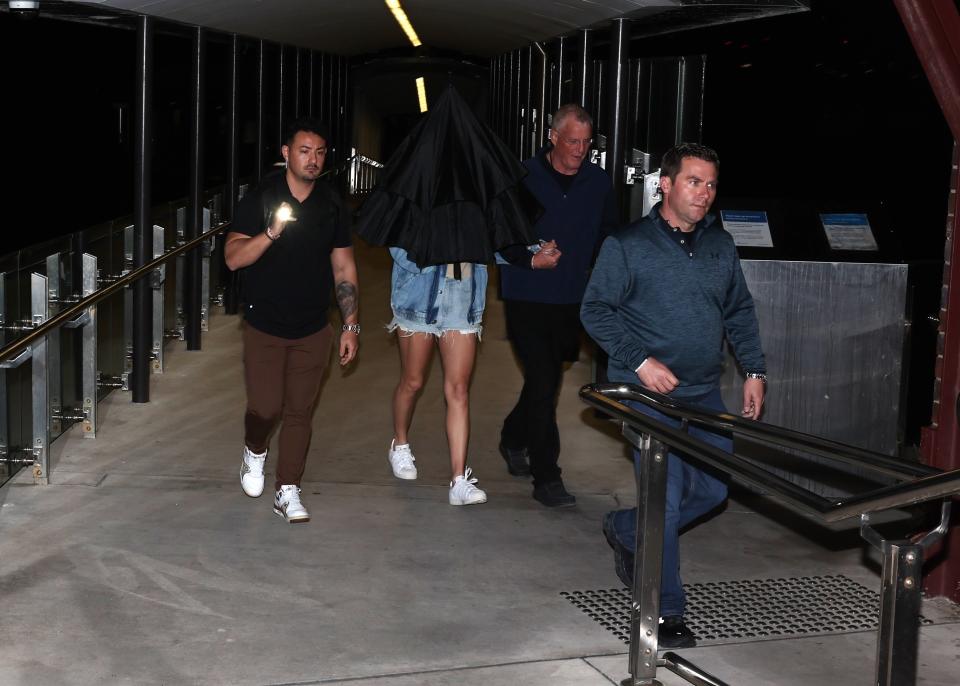 Taylor Swift with umbrella concealing her face walking hand in hand with her dad Scott Swift