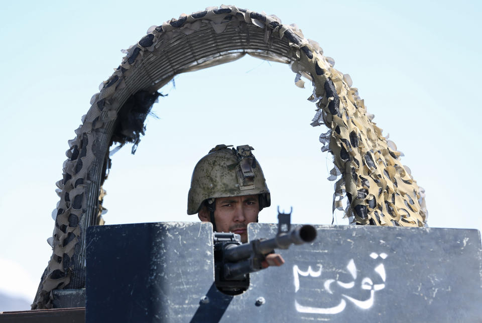 An Afghan special forces soldier stands guard in his vehicle at the site of a gun battle between Afghan security forces and insurgents in an Independent Elections Commission (IEC) office in Kabul, Afghanistan, Tuesday, March 25, 2014. Gunmen stormed into the building, trapping dozens of employees inside and killing many people. A candidate for a seat on a provincial council was among those killed, along with an election worker, a civilian and a policeman. (AP Photo/Massoud Hossaini)