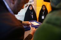 An Iranian man closes an empty ballot box before starting the vote at a polling station during parliamentary elections in Tehran