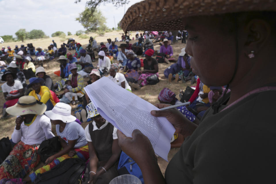 A woman reads out names of people waiting to receive food during a food distribution in Mangwe district southwestern Zimbabwe, amid a severe drought in Zimbabwe,Friday, March, 22, 2024. A new drought has left millions facing hunger in southern Africa as they experience the effects of extreme weather that scientists say is becoming more frequent and more damaging. (AP Photo/Tsvangirayi Mukwazhi)