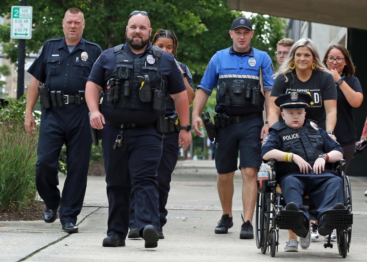 Gastonia Police Officer Caleb Price and others walk with Jr. Officer Jackson Hall and his mom, Jackie Hall, as they make their way along Main Avenue Monday morning, Aug. 28, 2023.