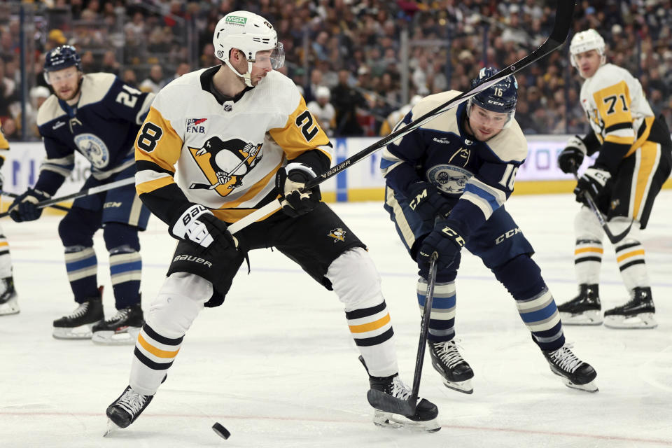 Pittsburgh Penguins defenseman Marcus Pettersson, left, works for the puck in front of Columbus Blue Jackets forward Brendan Gaunce during the second period of an NHL hockey game in Columbus, Ohio, Saturday, March 30, 2024. (AP Photo/Paul Vernon)