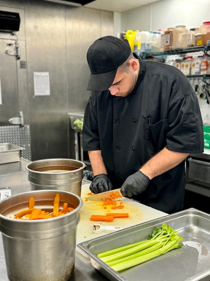 Zach Bower masters his knife skills in the kitchen of a St. Johns County retirement community. He is an intern in the school district's Project SEARCH career training program for young adult students with developmental differences.