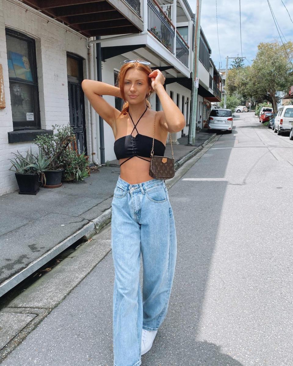 Woman in a black bikini top and jeans