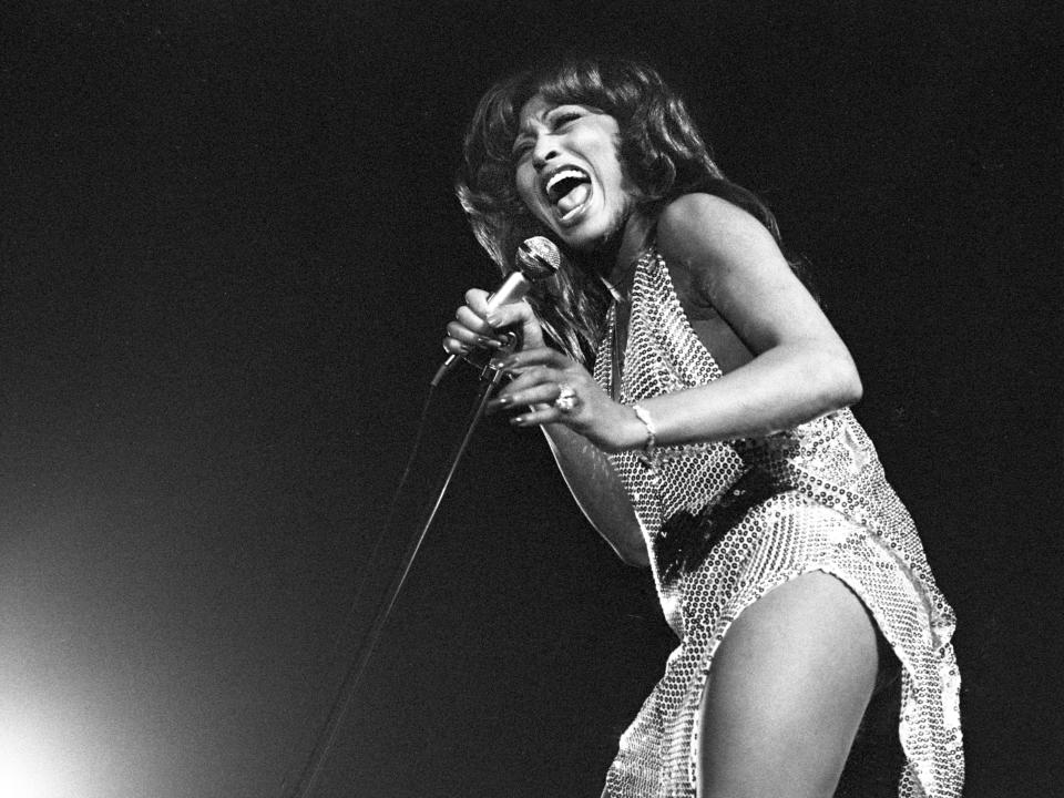 Tina Turner holding a microphone and singing