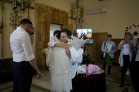 Kateryna Lytvynenko, center, embraces a relative after marrying Ihor Zakvatskyi, left, in Kyiv, Ukraine, Wednesday, June 15, 2022. Ihor proposed to Kateryna on the day the war started. A growing number of couples in Ukraine are speedily turning love into matrimony because of the war with Russia. Some are soldiers, marrying just before they head off to fight. Others are united in determination that living and loving to the full are more important than ever in the face of death and destruction. (AP Photo/Natacha Pisarenko)