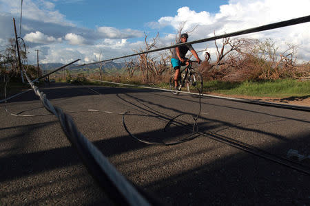 A man rides a bicycle by damaged electricity lines at an area affected by Hurricane Maria in Salinas, Puerto Rico, September 29, 2017 REUTERS/Alvin Baez