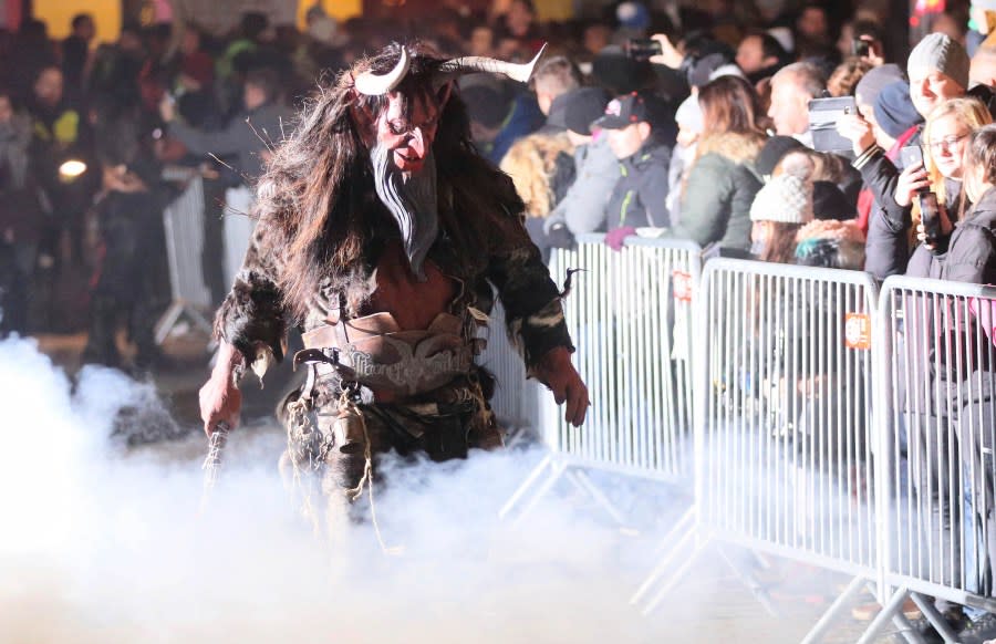 A Krampus scares spectators during a traditional Krampus run in which men and women dress up as pagan Krampus figures to scare people in Hollabrunn, Austria, Saturday, Nov. 30, 2019. (AP Photo/Ronald Zak)