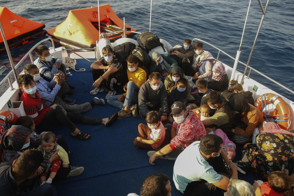 Migrants sit on a Turkish coast guard vessel after they were pulled off life rafts, during a rescue operation in the Aegean Sea, between Turkey and Greece, Saturday, Sept. 12, 2020. Turkey is accusing Greece of large-scale pushbacks at sea — summary deportations without access to asylum procedures, in violation of international law. The Turkish coast guard says it rescued over 300 migrants "pushed back by Greek elements to Turkish waters" this month alone. Greece denies the allegations and accuses Ankara of weaponizing migrants. (AP Photo/Emrah Gurel)