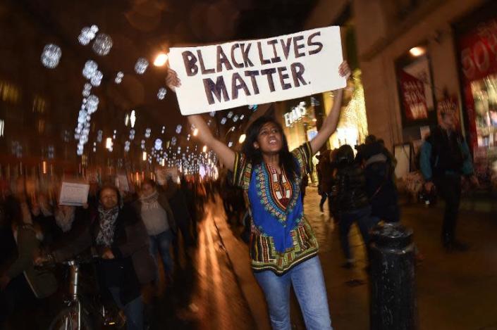 Demonstrators hold up placards and march down Oxford Street in central London on November 26, 2014 during a protest over the US court decision not to charge the policeman who killed unarmed black teenager Michael Brown (AFP Photo/Leon Neal)