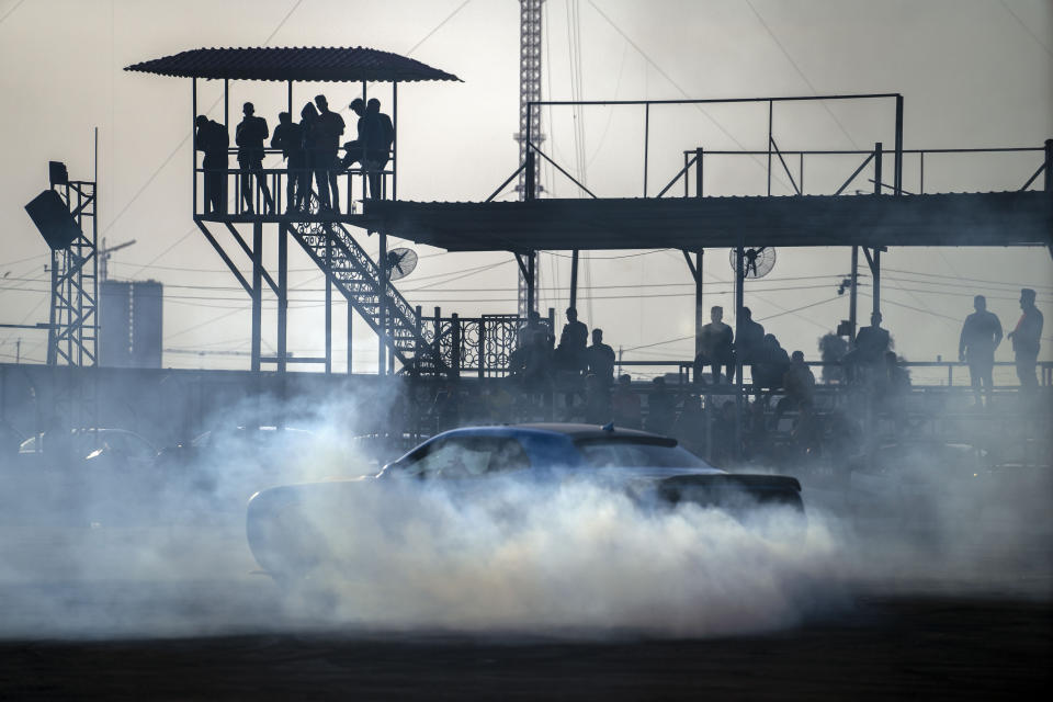 Muscle car aficionados gather at Baghdad's hippodrome to watch an informal drifting contest Friday, Feb. 24, 2023. Two decades after a U.S.-led invasion, Iraq’s capital today is full of life and a sense of renewal, its residents enjoying a hopeful, peaceful interlude in a painful modern history. (AP Photo/Jerome Delay)