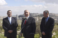 Israeli Prime Minister Benjamin Netanyahu, center, stands with Jerusalem Mayor Moshe Leon, left, as he announces a new neighborhood is to be built in the Israeli West Bank Israeli settlement of Har Homa, Thursday, Feb. 20, 2020. (Debbie Hill/Pool via AP)