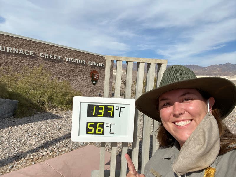 An employee of Death Valley National Park poses next to an interpretive display showing the newly record breaking temperature in Death Valley National Park