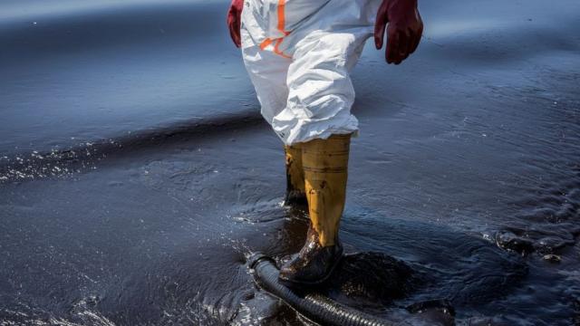Un trabajador camina en agua contaminada por petr&#xf3;leo