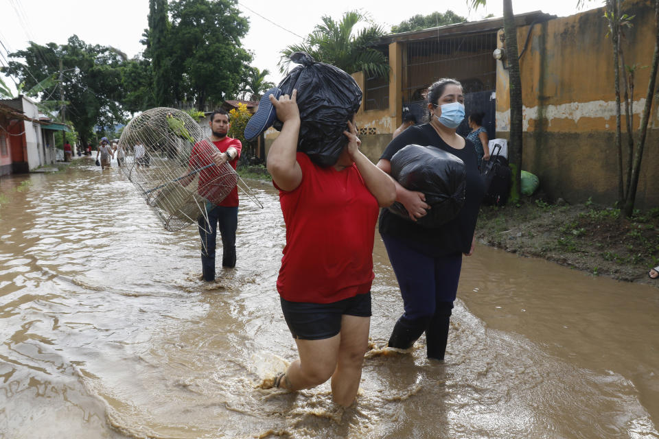 Residents carrying belongings wade through floodwaters in the neighborhood of Suyapa, Honduras, Thursday, Nov. 5, 2020. The storm that hit Nicaragua as a Category 4 hurricane on Tuesday had become more of a vast tropical rainstorm, but it was advancing so slowly and dumping so much rain that much of Central America remained on high alert. (AP Photo/Delmer Martinez)