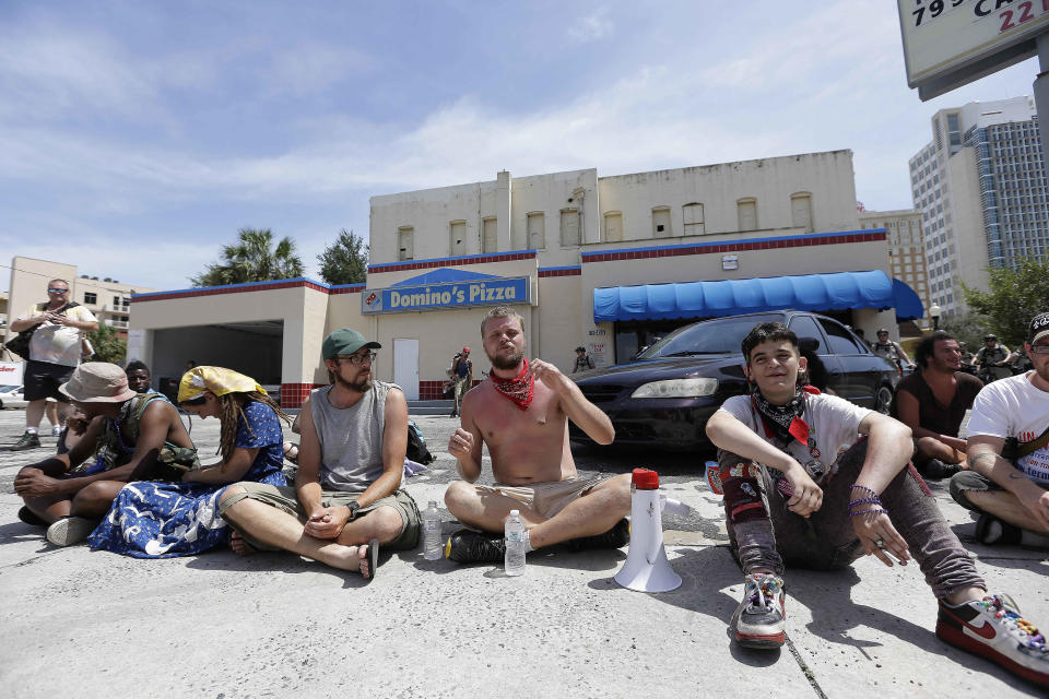 A few demonstrators sit on a Domino's Pizza parking lot in protest, Thursday, Aug. 30, 2012, in Tampa, Fla. The three dozen chanting anti-GOP protesters hit a lull of silence as they marched through a neighborhood of low-income housing in west Tampa. "What are you guys doing taking a nap?" shouted one protester to his cohorts. Another shouted, "You guys are reeeeaaal quiet, now!"  The protests against the Republican convention in Tampa have been unexpectedly muted this week, something even the protesters acknowledge. (AP Photo/Chris O'Meara)