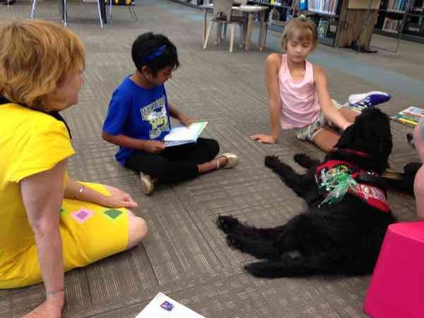 Islands children's librarian Sha Dishong, left, with Sahasra, 7, center, reading to Labradoodle Bella.