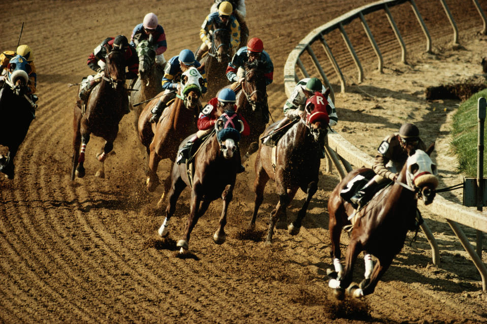 Horse racing event showing jockeys on horses mid-race on a dirt track