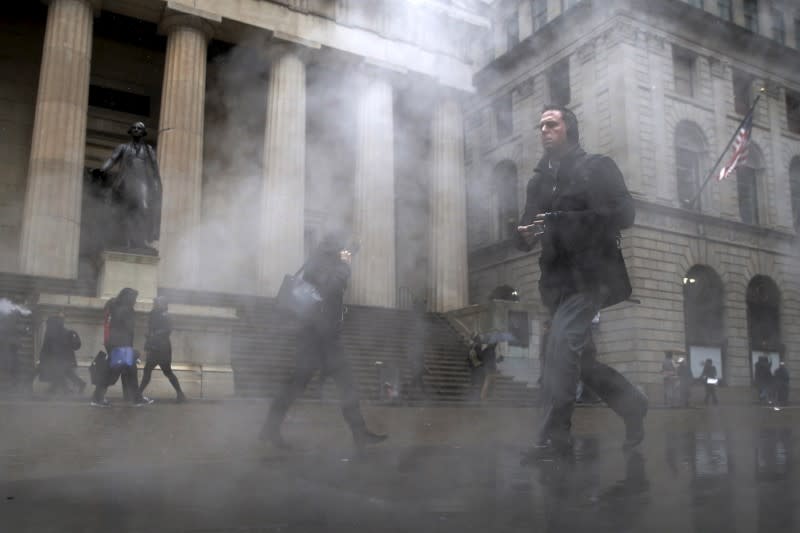 Morning commuters walk through a steam cloud on Wall St. during a morning snow fall in New York's financial district