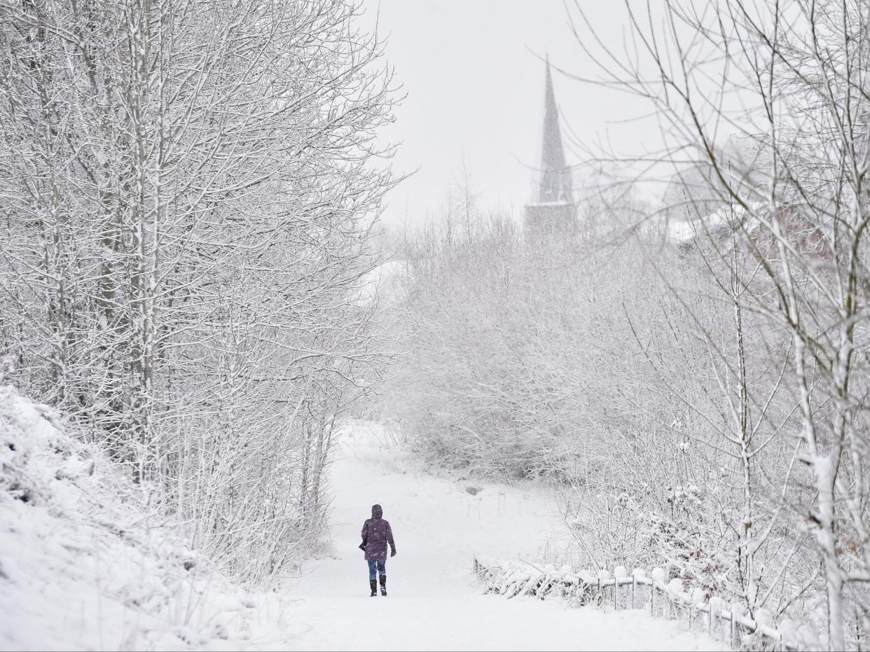 A lady walks in the snow past Silverdale Church on 29 December in Newcastle-Under-Lyme, England (Getty)