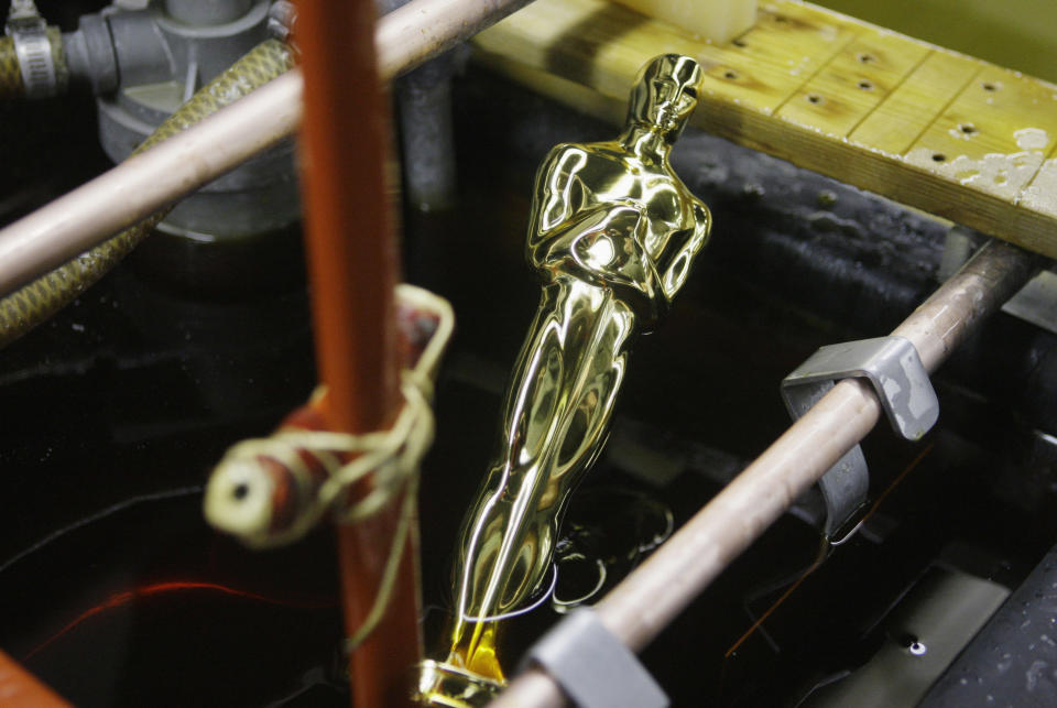FILE - In this Jan. 26, 2009 file photo, an Oscar statue is pulled from the final plating process that coats the statue with 24-karat gold at R.S. Owens & Co., in Chicago. The company said it will be laying off 95 workers on Dec. 17, 2012. The cuts come a month after the company announced it was being purchased on Dec. 17 by St. Regis Crystal Inc. of Indianapolis. They have about 250 employees. A news release on the sale said the company will continue to make Oscar and Emmy statues in Chicago. They have been making the Oscar statues for about 30 years. (AP Photo/M. Spencer Green, File)