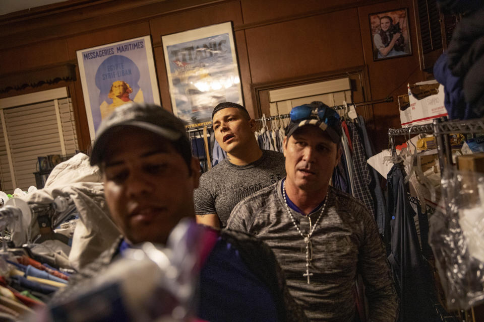 Ariel Forcade, from left, Ancermo Rivero and Yasnier Palacio Nieves, all asylum seekers from Cuba, browse clothing in a donation room set up in the home of Rita Ellis, a founding member of the organization Paz Amigos, Wednesday, Nov. 6, 2019, in Columbus, Ga. When detainees are released, it's often in the evening. If they aren't fortunate enough to have family waiting for them in the parking lot, they're driven 30 minutes away to Columbus and left at one of two bus stations in town. (AP Photo/David Goldman)