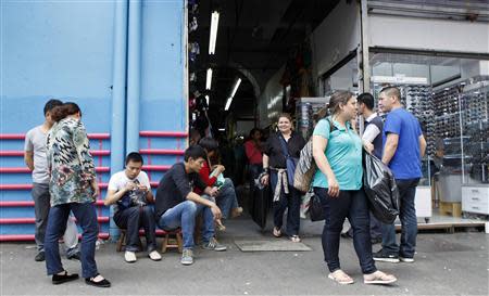 Local residents walk past Chinese immigrants in front of a store in downtown Sao Paulo October 30, 2013. REUTERS/Paulo Whitaker